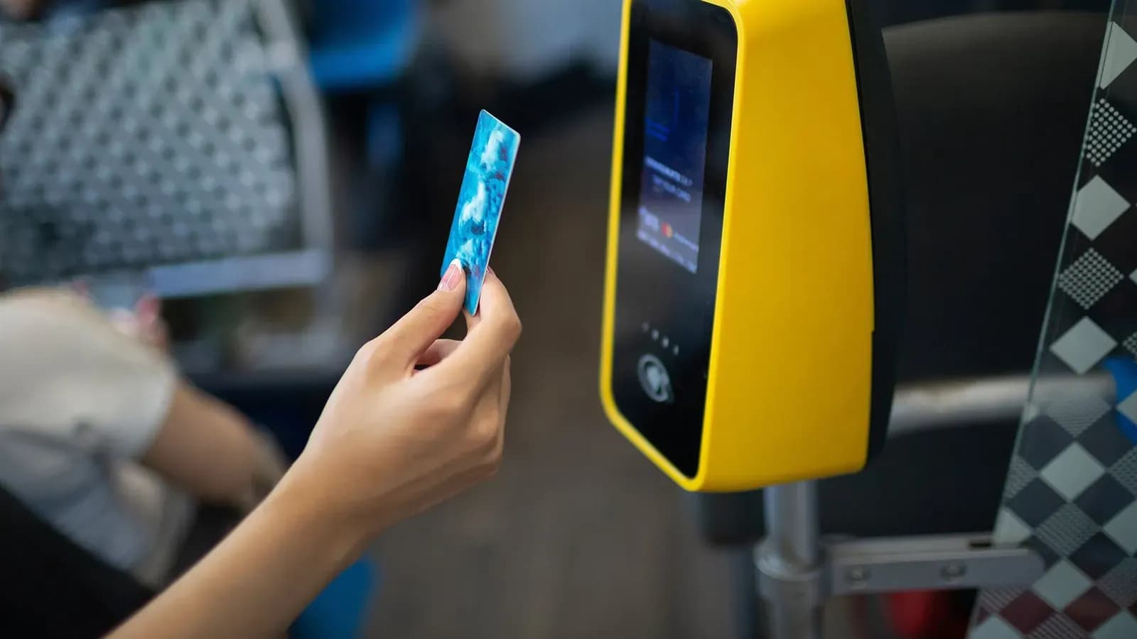 A passenger tapping a bank card on a bus validator